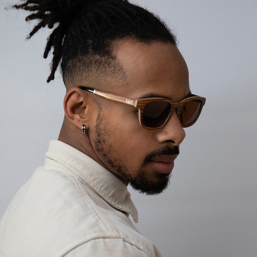 Black man wearing  Eco conscious wooden sunglasses with light coloured wood looking down