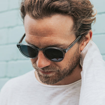 Man looking down wearing clear grey frame sunglasses with polarised lenses